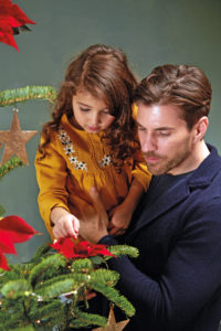 Jente på pappas arm ser på juletreet